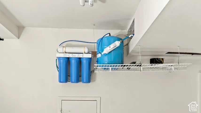 Wall-mounted multi-stage water filtration system featuring a pressurized storage tank and integrated wire shelving