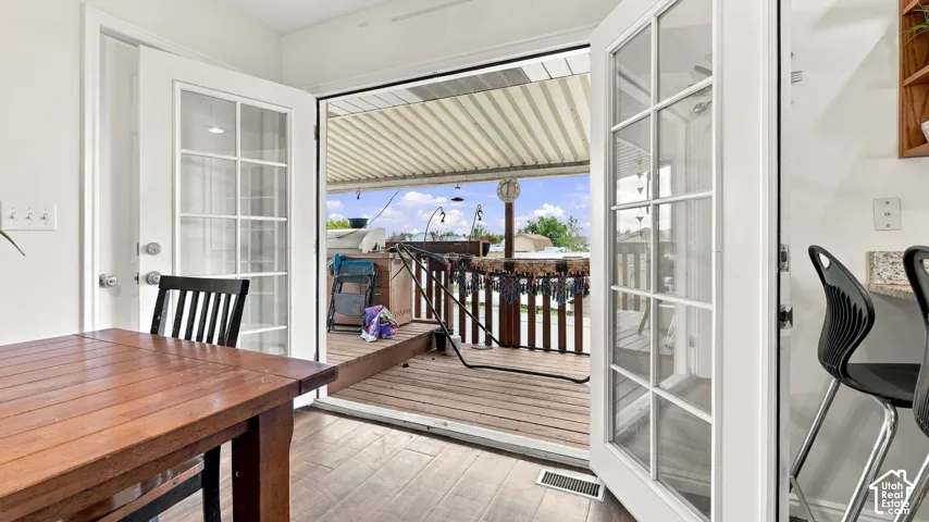 Glass-paned French doors opening to a wood-decked patio featuring a slatted roof cover and wooden railing