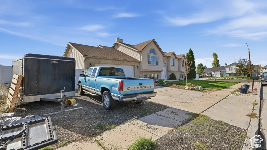 Split-level exterior featuring light-toned brick and siding, an asphalt shingle roof, arched window detailing, and an attached two-car garage