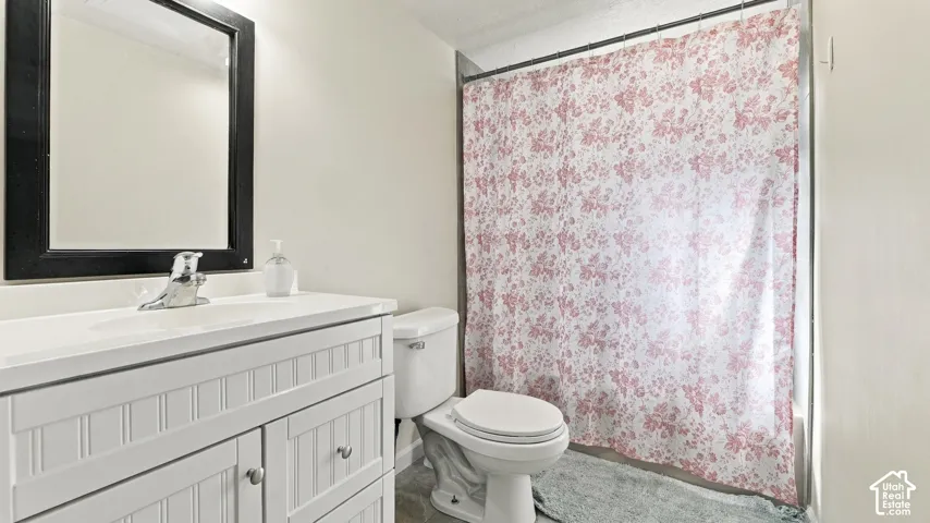 White vanity with beadboard-style cabinet doors, integrated countertop and sink, chrome-finish faucet, and black-framed wall mirror