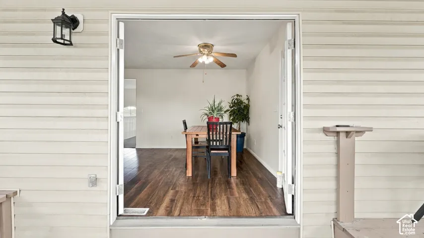 Exterior wall featuring horizontal siding, a mounted wall lantern, and double-door entry with wood-finish flooring and a central ceiling fan
