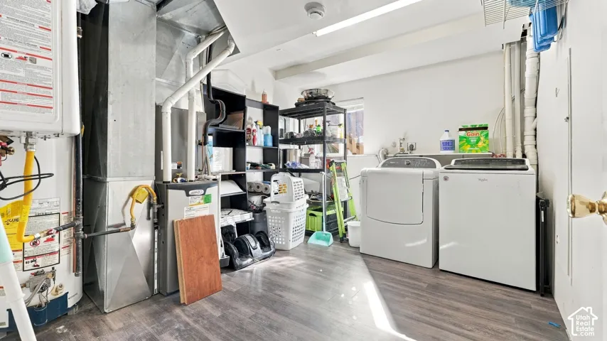 Utility room featuring wood-finish flooring, a wall-mounted tankless water heater, and a high-efficiency forced air furnace