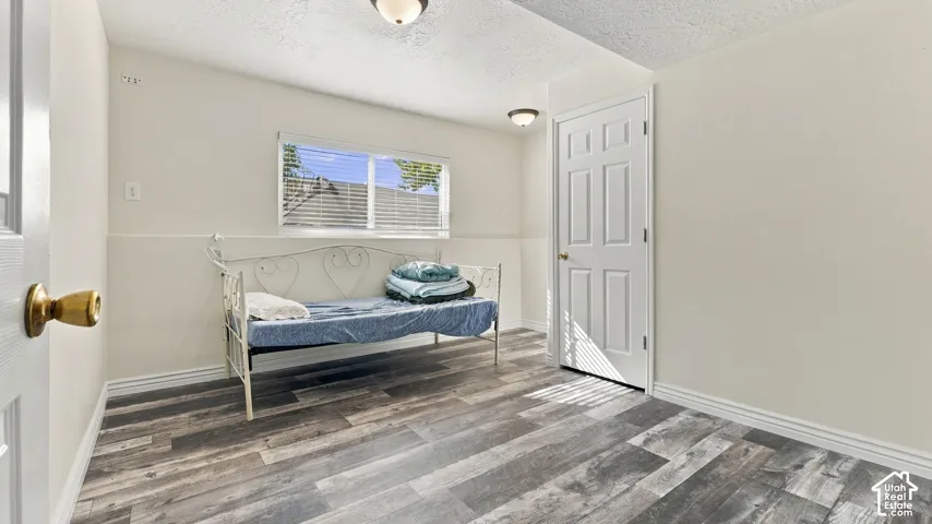 Room featuring neutral-toned wall paint, wood-finish flooring, a six-panel door with metallic hardware, and two flush-mount ceiling light fixtures