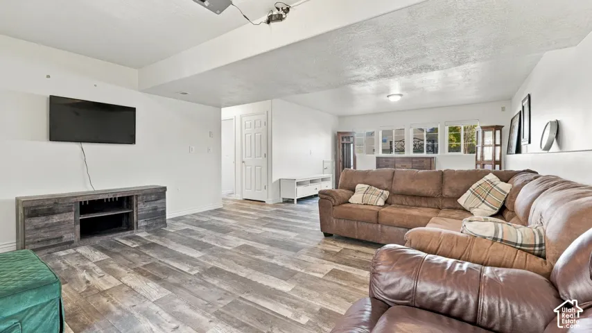 Open-concept interior featuring wood-finish flooring, a built-in media console, white wall finishes, and multiple windows with shutter-style coverings