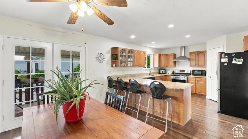 Kitchen featuring wood-finish cabinetry, stone-surface countertops, peninsula seating, stainless steel appliances, and recessed lighting