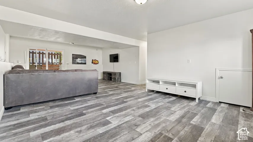 Open-concept interior featuring wood-finish plank flooring, smooth-finish ceilings, recessed lighting, and sliding glass door access