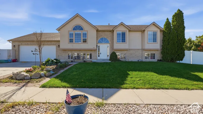 Exterior featuring a mixed brick and stucco facade, arched windows, an attached two-car garage, and landscaped front lawn