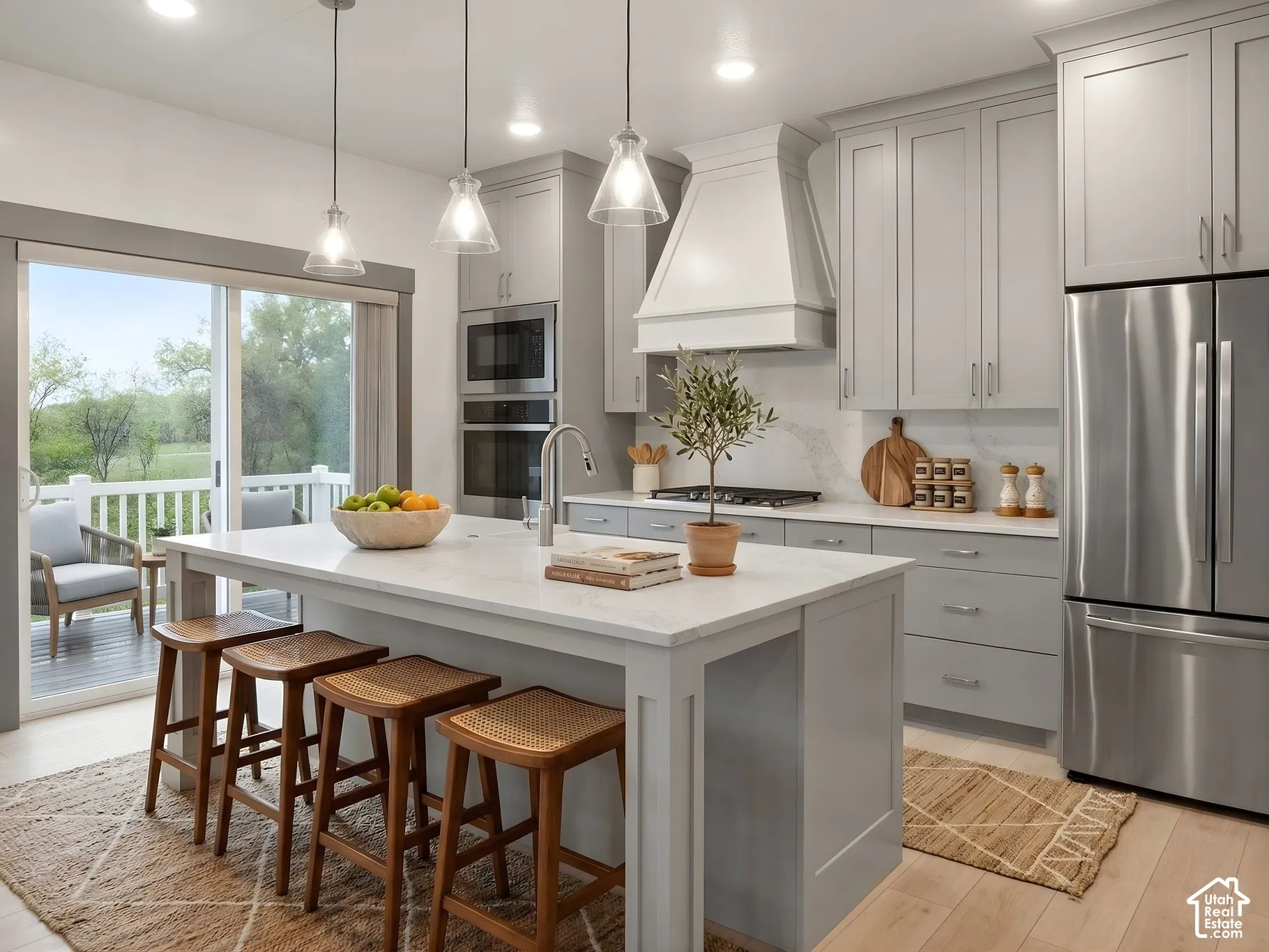 Kitchen featuring light-gray shaker-style cabinetry, quartz countertops, stainless steel appliances, a custom range hood, and wood-finish flooring