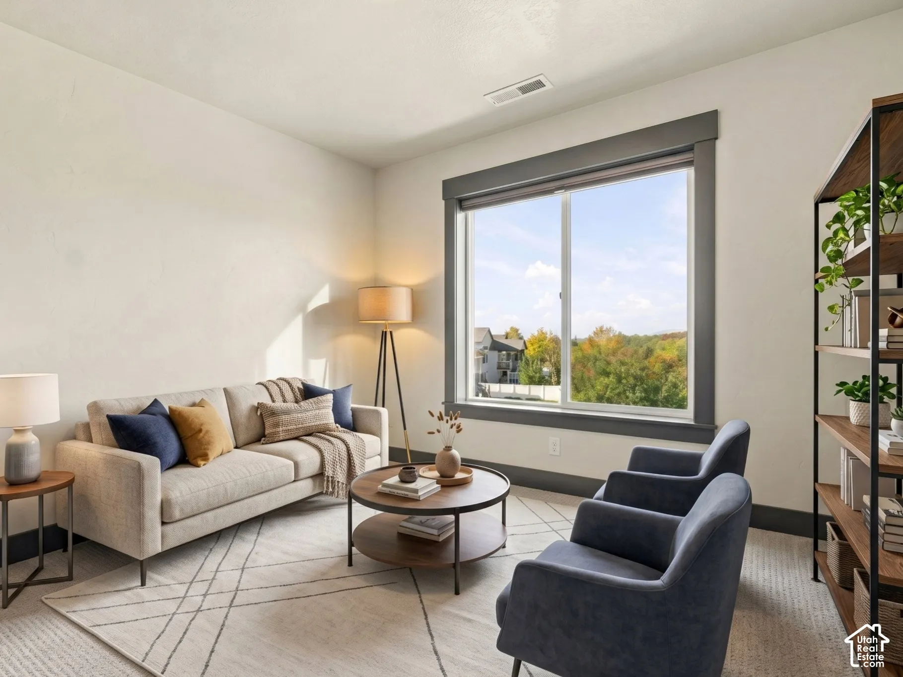 Neutral-toned interior space featuring light-colored wall-to-wall carpeting, expansive windows with dark-finished trim, and natural exterior scenery