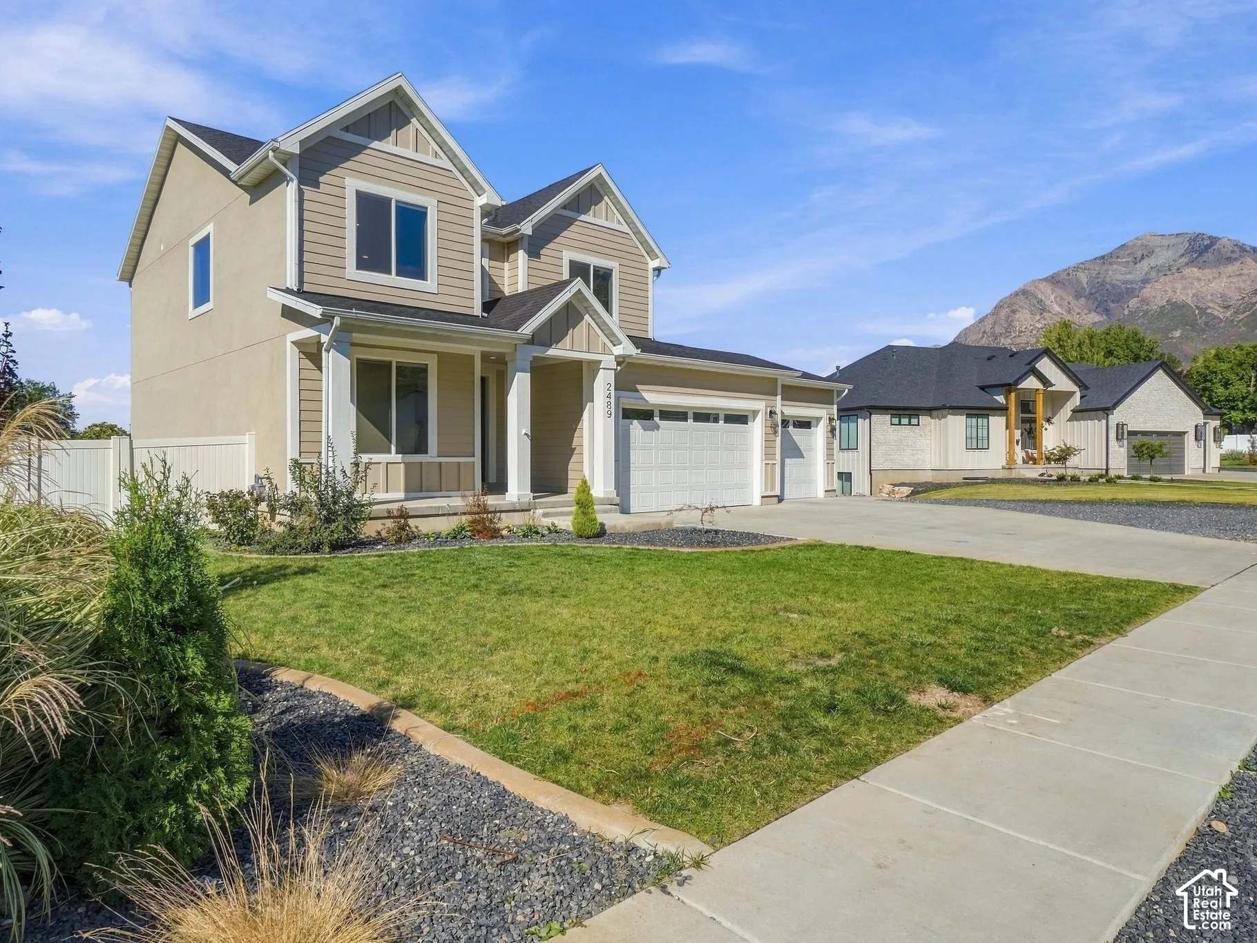 Two-story residence featuring a multi-gabled roofline, horizontal siding exterior, concrete driveway, attached three-car garage, and mountain backdrop