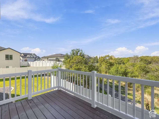 Raised deck featuring synthetic wood-finish decking and white composite railing, overlooking a fenced backyard and mature tree line