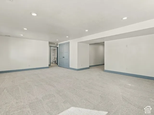Expansive interior room featuring neutral carpeting, recessed lighting, and painted grey dual-panel closet doors