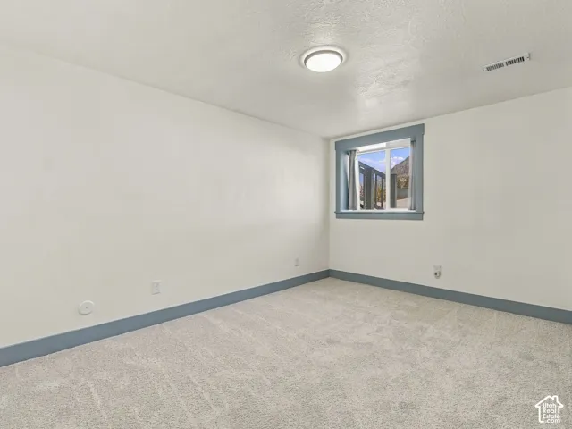 Interior room featuring neutral-toned carpeting, minimalist ceiling lighting, and blue-toned window and floor trim