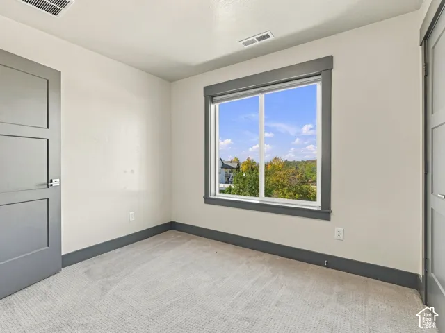 Interior space featuring light-toned carpeting, two-panel interior doors with metallic lever handles, and a window with gray trim casing
