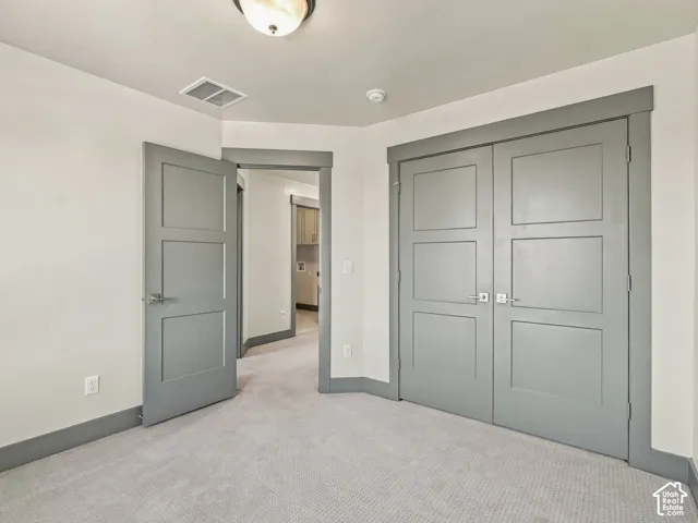 Neutral interior featuring three-panel gray doors, matching wide-profile door casing, plush wall-to-wall carpeting, and a flush-mount overhead light fixture