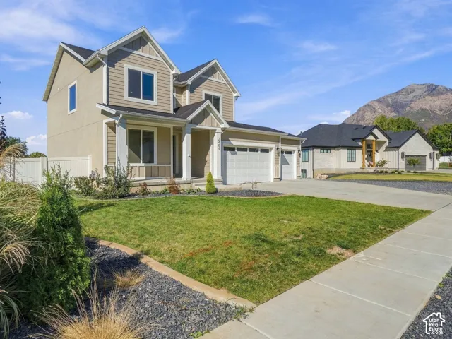 Two-story residence featuring a multi-gabled roofline, horizontal siding exterior, concrete driveway, attached three-car garage, and mountain backdrop