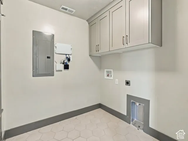 Utility space featuring wall-mounted shaker-style cabinetry, hexagon-patterned tile flooring, and integrated laundry hookups