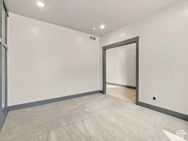 Neutral carpeting, wall-mounted grid wainscoting, and deep-toned door casing framing the entryway