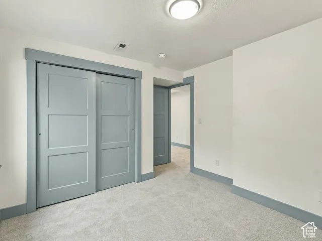 Neutral interior room featuring plush carpeting, dual-panel sliding closet doors, and contrasting painted wood trim