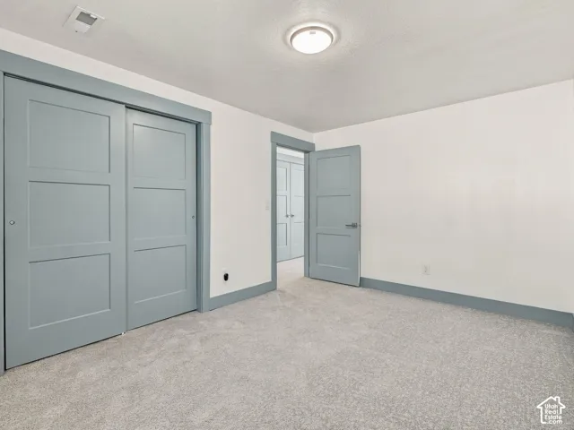 Neutral-toned interior space featuring light blue three-panel doors, matching blue door trim, neutral wall-to-wall carpeting, and a central flush-mount ceiling light fixture