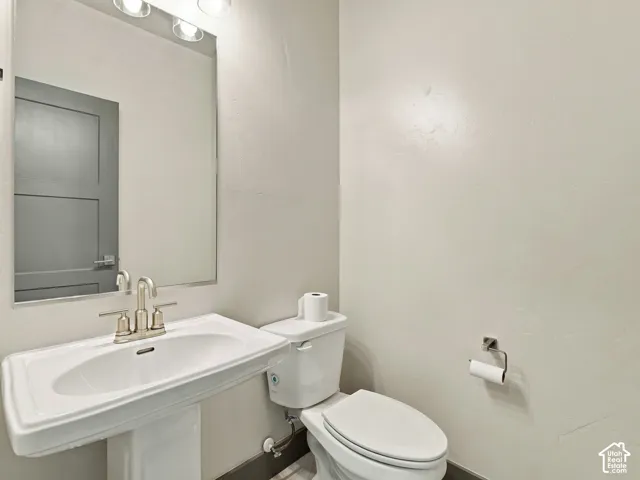Powder room featuring a pedestal sink, brushed nickel widespread faucet, wall-mounted mirror, and multi-light vanity fixture