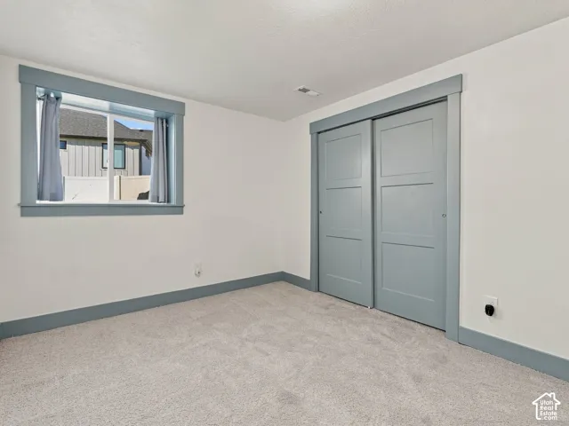 Neutral wall paint, plush carpeting, sliding-door closet, and window with casing and trim in a muted blue finish