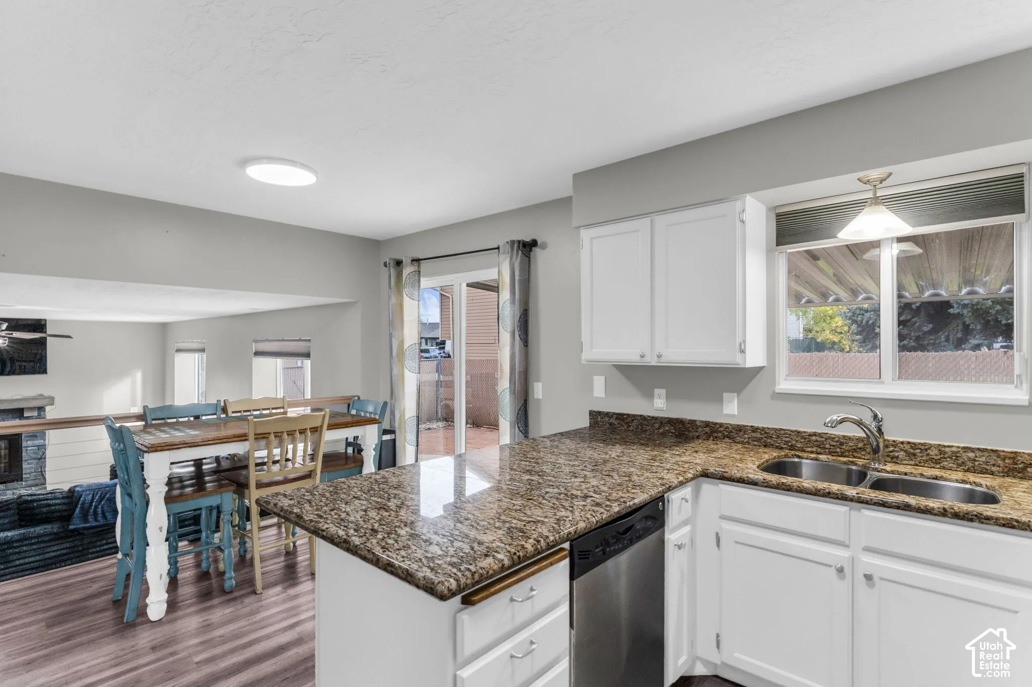 Kitchen featuring white cabinetry, stone countertops, stainless steel dishwasher, dual-basin sink, and wood-finish flooring
