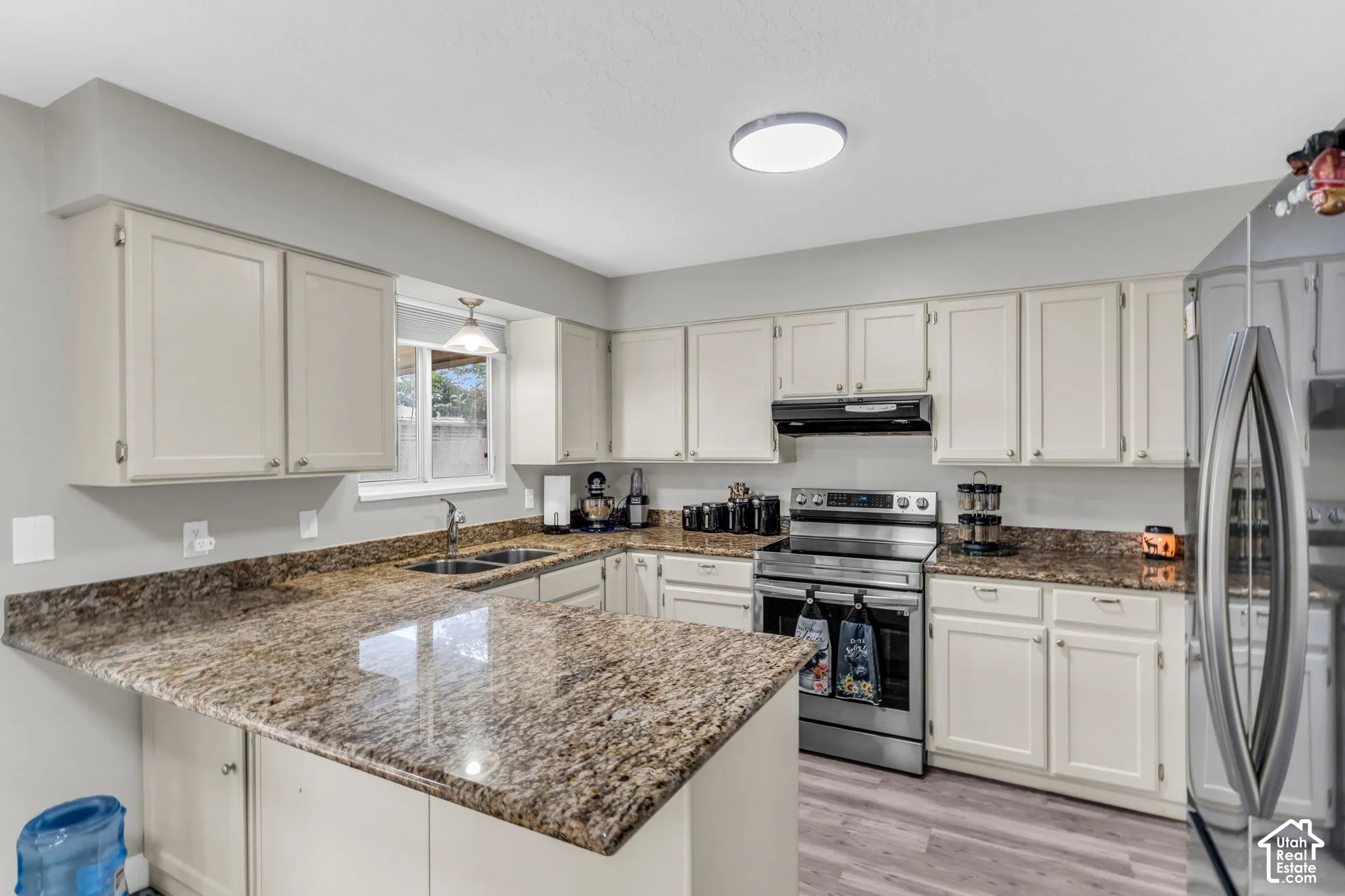 Kitchen featuring neutral cabinetry, stone-finish countertops, stainless steel appliances, and wood-finish flooring