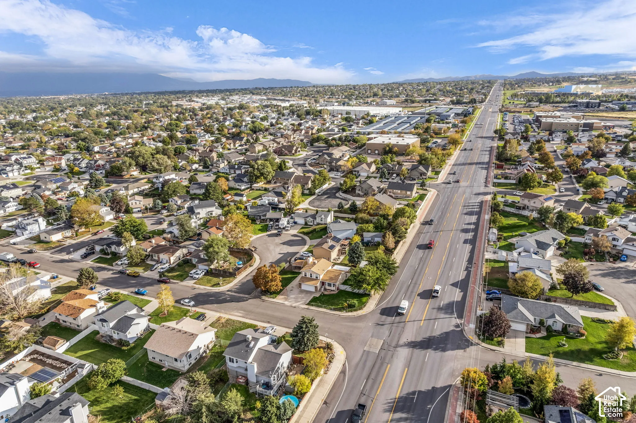 Aerial view of a residential neighborhood featuring established tree growth, suburban density, and mountain range backdrop