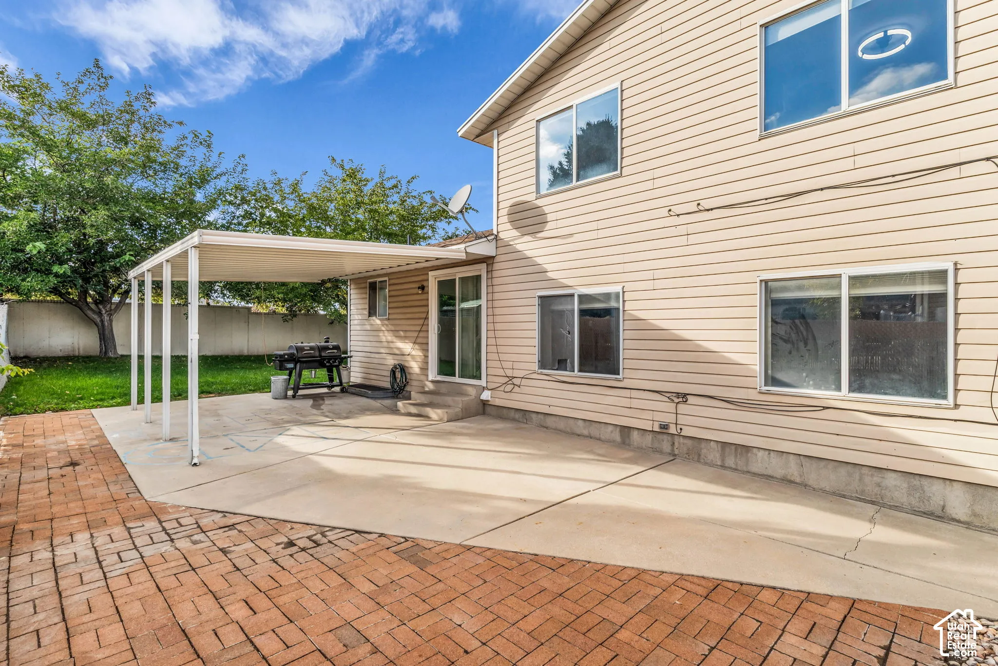 Exterior space featuring a concrete patio, a covered structural pergola, and brick-style paver hardscaping