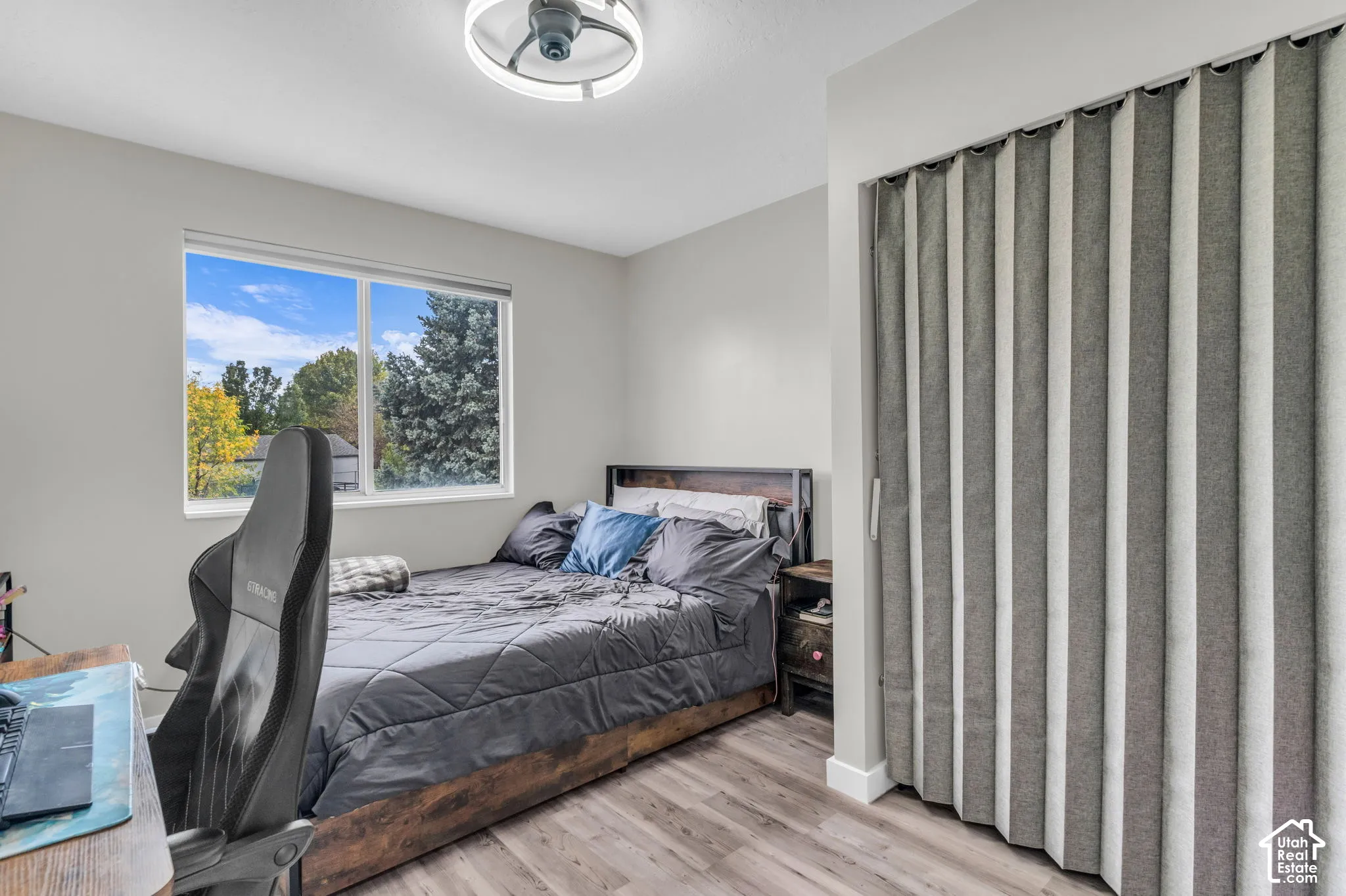 Neutral paint palette, wood-finish flooring, recessed window, and accordion-style closet door featuring a circular flush-mount ceiling light fixture