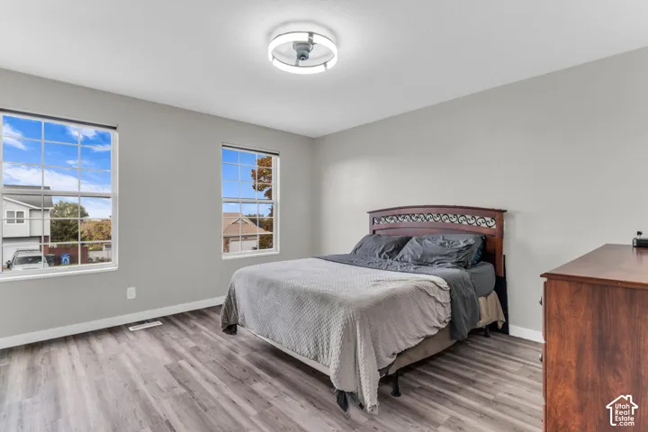 Neutral-toned interior featuring wood-finish flooring, dual grid-pattern windows, and a circular flush-mount ceiling light