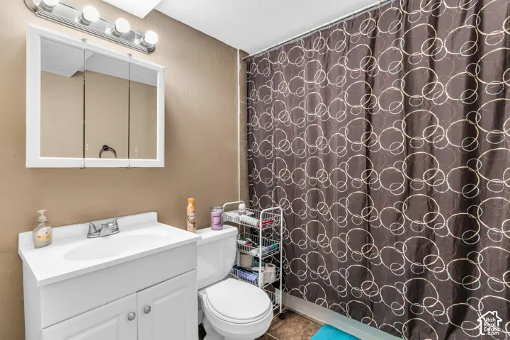 Bathroom featuring a white vanity cabinet with an integrated sink, a three-door mirrored medicine cabinet, and a multi-bulb vanity light fixture