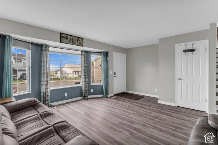 Living area featuring wood-finish flooring, a multi-pane bay window, and a paneled entry door