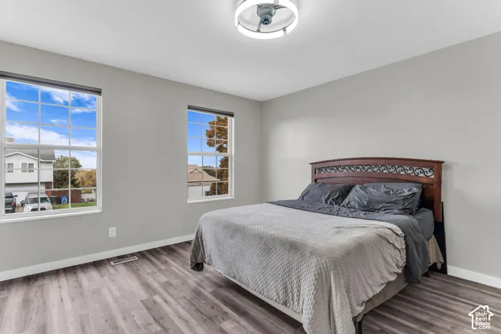 Wood-finish flooring, neutral wall tones, two large dual-pane windows with muntins, and a contemporary circular flush-mount ceiling fixture