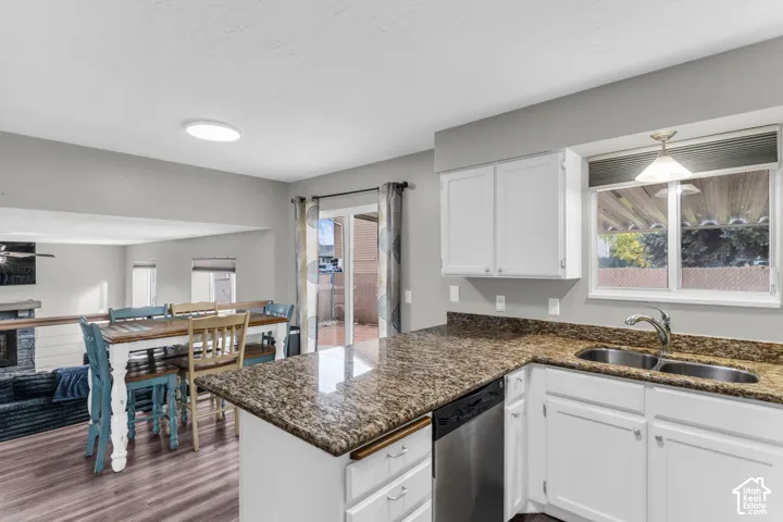 Kitchen featuring white cabinetry, stone countertops, stainless steel dishwasher, dual-basin sink, and wood-finish flooring