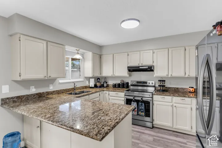 Kitchen featuring neutral cabinetry, stone-finish countertops, stainless steel appliances, and wood-finish flooring