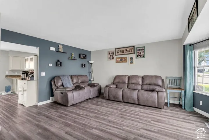 Living area featuring wood-finish flooring, a bold accent wall, and a bay window
