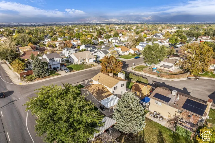 Aerial perspective featuring a multi-level residential property with installed roof-mounted solar panels, wood-tone roof shingles, and expansive mountain scenery