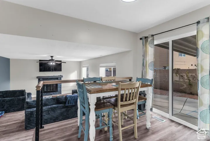Wood-finish flooring, fireplace with stone-style surround, metal railing, and sliding glass door with access to a paved patio