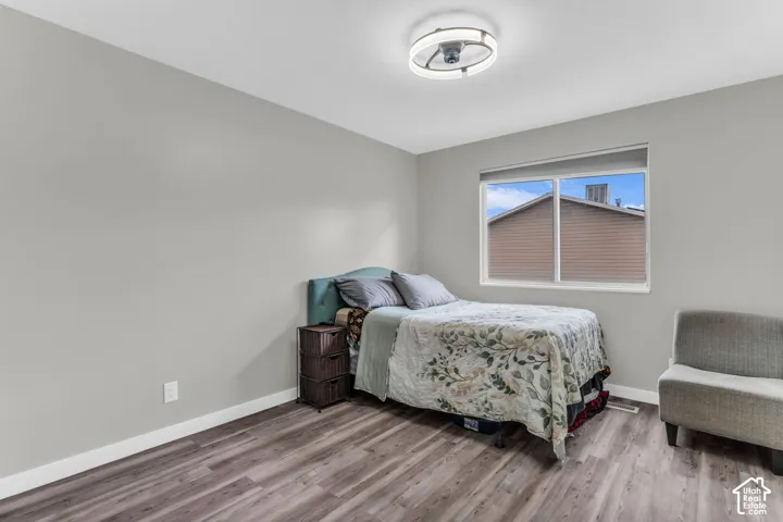 Neutral-toned interior room featuring wood-finish flooring, a large sliding window with integrated shade, and a contemporary circular flush-mount ceiling fixture