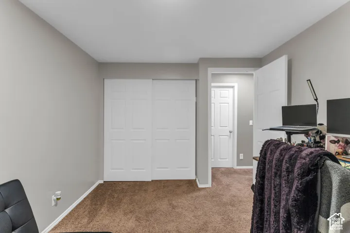 Neutral-toned interior room featuring plush carpeting, white six-panel closet doors, and matching white interior passage doors