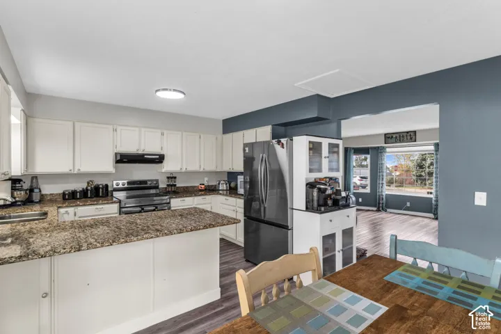 Kitchen featuring white cabinetry, stone-finish countertops, stainless steel appliances, and wood-finish flooring