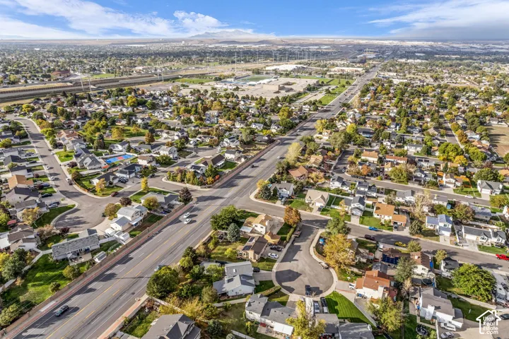 Aerial perspective of a suburban neighborhood featuring tree-lined streets, established residential lots, and distant mountain scenery