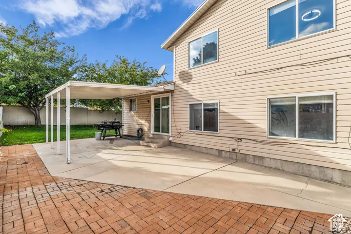 Exterior space featuring a concrete patio, a covered structural pergola, and brick-style paver hardscaping