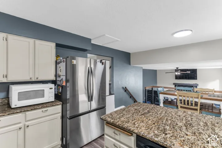 Kitchen featuring stone countertops, stainless steel refrigerator, light-toned cabinetry, and recessed lighting