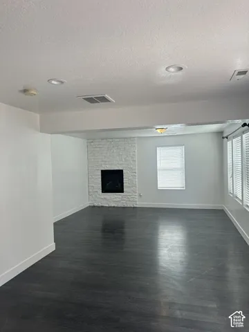 Living area featuring dark wood-finish flooring, recessed lighting, and a white stone-texture fireplace surround