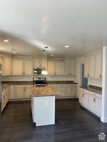 Kitchen featuring wood-finish flooring, cream-toned cabinetry, a center island, laminate countertops, and recessed lighting