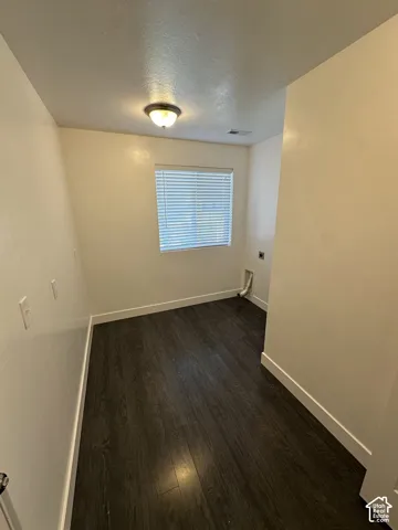 Neutral-toned walls featuring wood-finish flooring, a flush-mount ceiling light fixture, and a window with horizontal blinds