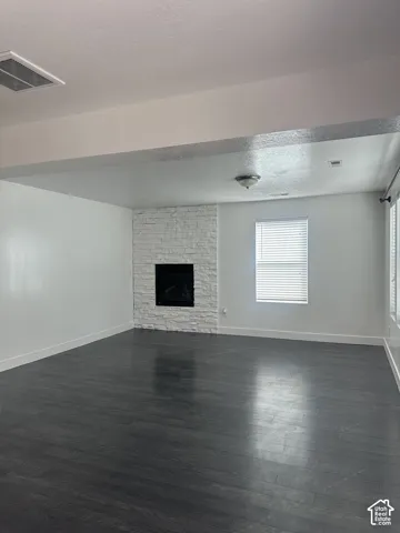 Fireplace with a white stone surround, dark wood-finish flooring, and recessed ceiling lighting